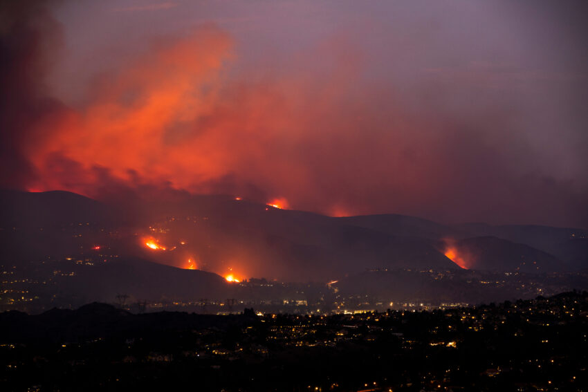A wildfire burning through California hills at night