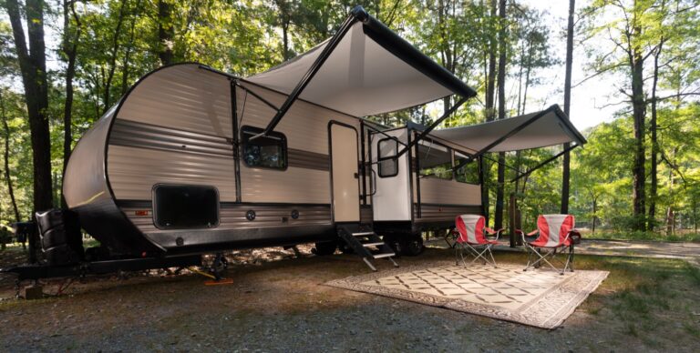 A large travel trailer parked at a wooded campground site